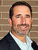 A headshot of Jason Amrich in front of a brick wall.