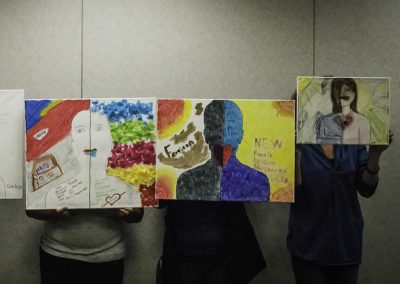 Three Project Hope Self Portrait Paintings held in front of each artist's face.