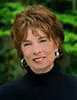 Rosalind Cook wearing a black turtleneck in front of bright greenery.