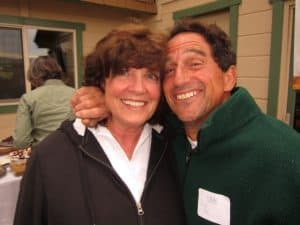 Donors Sandra and John Cosentino hug and smile at an event in a restaurant.