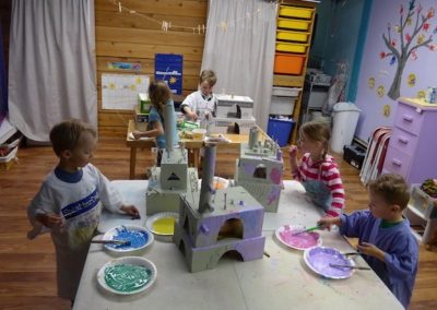 Five young children paint castles they made from cardboard at the Trailhead Museum. Photo by Claudia Brauer.