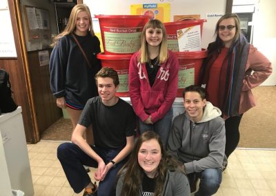 Six WSCU Student Hall Council Members stand in front of the red buckets of food they gathered when they led a Food Drive.