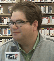 Drew Brookhart speaking in front of a mic in the library.