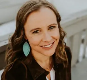 Annie Callahan smiles wearing a large turquoise earring and a black jacket.