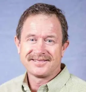 Headshot photo of Paul Duba with a blue background.