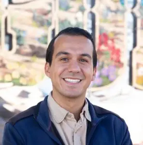 Ricardo Esqueda smiling in front of the Gunnison IOOF Park mural.