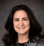 Claudia Helguero smiles in this headshot with a dark background.