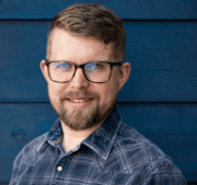 Dark blue house siding and a blue plaid shirt set off Brett Henderson's smile.