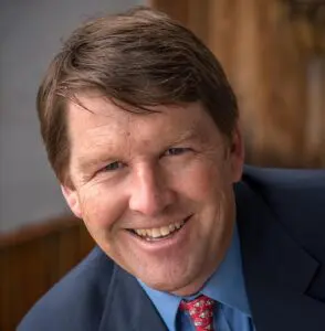 Jeff Moffett wears a coat and tie and smiles as he leans toward the camera.