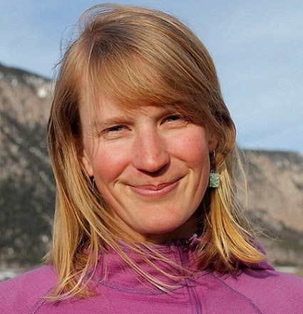 Hedda Peterson quietly smiles in a pink jacket from the field in front of Mt. Crested Butte.