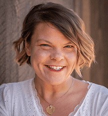 Erica Rasmussen smiles wearing a short hair style and a white top.