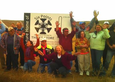 A group of clients wmile and raise their hands in front of the Six Points Sign.