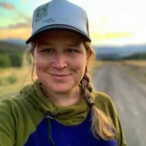 Ashley Upchurch is on a dirt country road wearing a ball cap and braided hair.