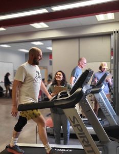 A man walks on a tredmill at Wellness Elevated while a trainer looks on.