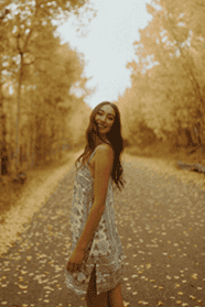 Adelene Frymoyer playfully posing on a dirt road surrounded by yellow aspen.