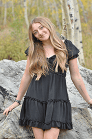 Izabella Hartzell leaning against a rock in a yellow aspen grove