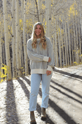 Ryann Nordberg standing in front of a stand of aspens with the sun shining on her