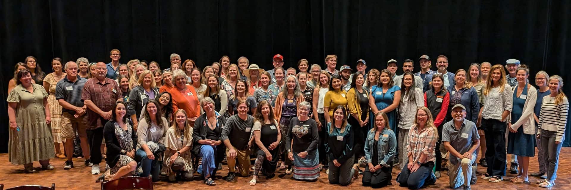 group shot of many people working in the nonprofit sector posed in several rows in front of a black curtain