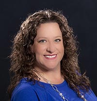 smiling woman with curly dark hair and blue shirt