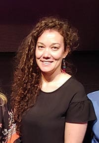 smiling woman with long curly dark hair and black shirt