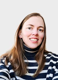 smiling woman with light brown hair wearing navy and white striped sweater