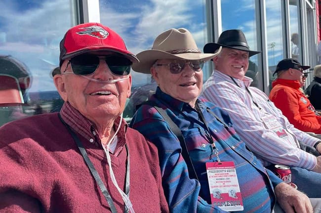 Three older men watching the Western Colorado University Football team at the Mountaineer Bowl Stadium