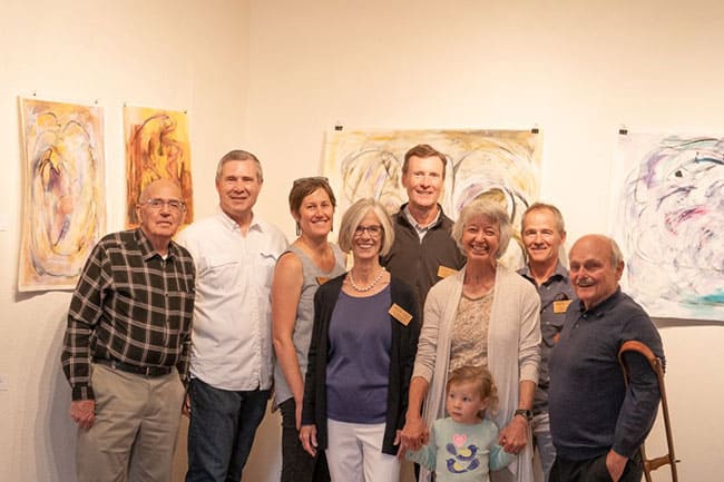 group of 9 smiling people of all ages in an art gallery