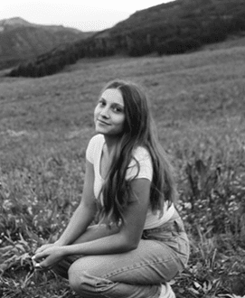Sienna Gomez Izabella Hartzell leaning against a rock in a yellow aspen grove