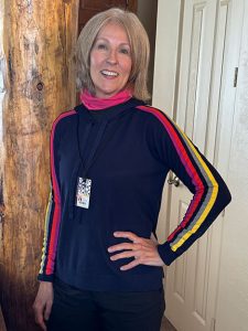 lisa-rodman-2 smiling woman with short blonde hair wearing navy blue skiing top with colorful stripes on the sleeves