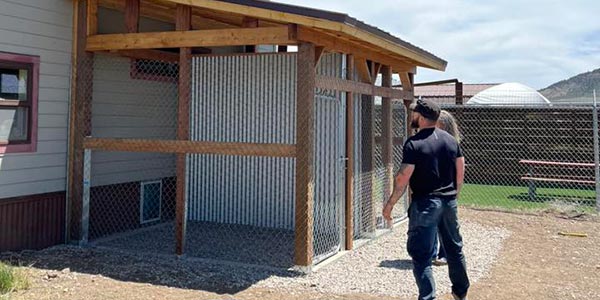 two people inspecting two new kennels built onto the outside of the Gunnison Valley Animal Welfare League Shelter building