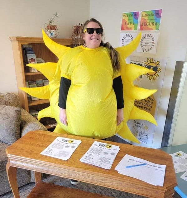 Katie Lew Katie Lewinger smiling and wearing sunglasses and a blow-up sun costume.