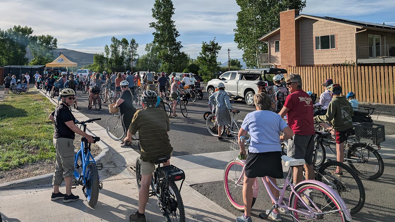 people on bikes lining up for a music cruise on a sunny summer evening