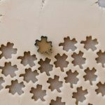 A small clover cookie cutter making a repeated pattern in cookie dough