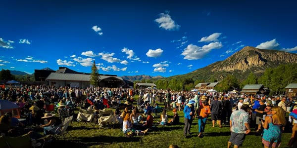 large crowd of concert-goers on lawn at Center for the Arts during Alpenglow with blue sky and Crested Butte Mountain in the background
